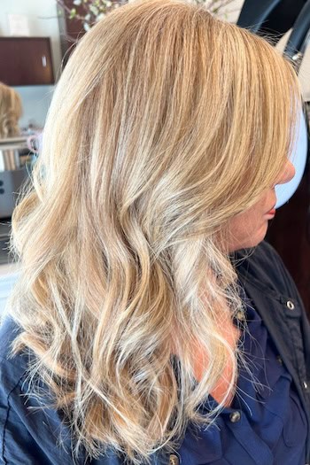 Textured Blonde Waves Hairstyle, side view, on a woman in her fifties with thick hair.