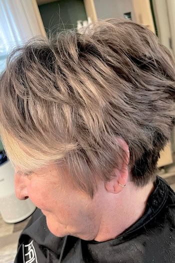 Voluminous Ash Blonde Pixie With Swoop Bangs Haircut, side view.