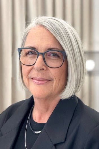 Straight Silver Chin-Length Bob Hairstyle on a woman in her 60s wearing glasses.