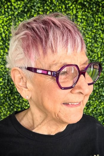 Textured Silver Mauve Pink Pixie Hairstyle on a woman in her 60s wearing glasses.