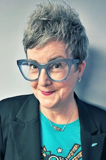 Spiky Textured Gray Pixie Hairstyle on a woman in her 60s wearing glasses.