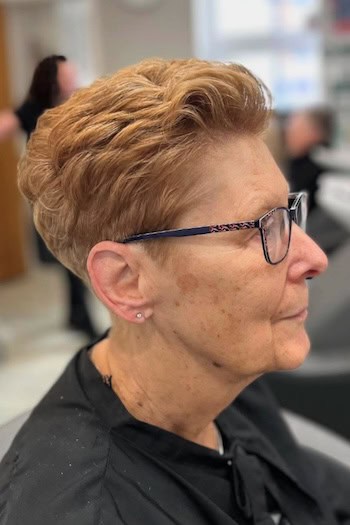 Textured Copper Pixie With Lift Hairstyle on a woman in her 60s wearing glasses, side view.