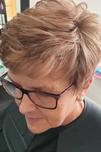Feathered Pixie Hairstyle on a woman in her 60s wearing glasses.