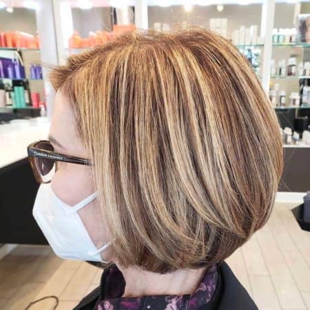 Highlighted Medium Bob Hairstyle on a woman in her 60s wearing glasses, side view.