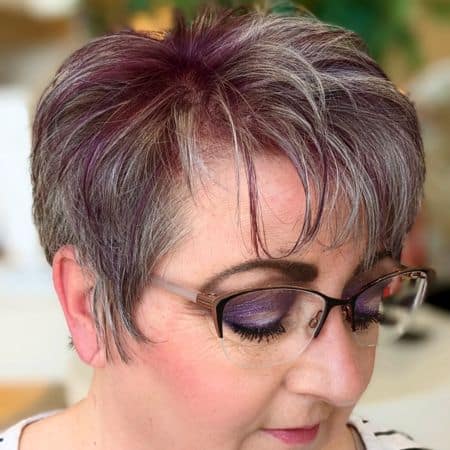 Silver Pixie With Deep Violet Highlights Hairstyle on a woman in her 60s wearing glasses.