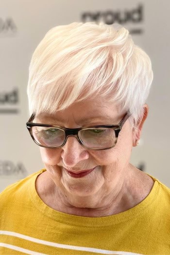 Brushed Forward Pixie With Longer Top Hairstyle on a woman in her 60s wearing glasses.