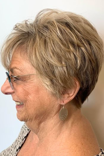 Voluminous Layered Pixie Hairstyle on a woman in her 60s wearing glasses, side view.