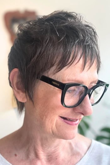 Short Pixie With Textured Top Hairstyle on a woman in her 60s wearing glasses.