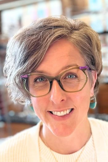 Long Textured Pixie with Side Sweep Hairstyle on smiling woman with glasses in her 50s.