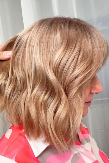 Honey Blonde Wavy Long Bob with Bangs Hairstyle, side view.
