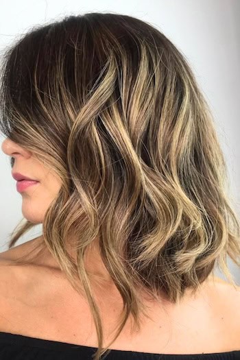 Brunette Long Wavy Bob with Delicate Blonde Highlights Hairstyle, side view.
