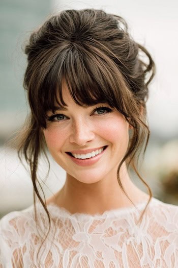 Voluminous Updo with Bangs and Loose Tendrils Hairstyle
